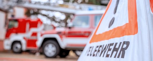 Feuerwehrfahrzeuge mit Warnschild im Vordergrund