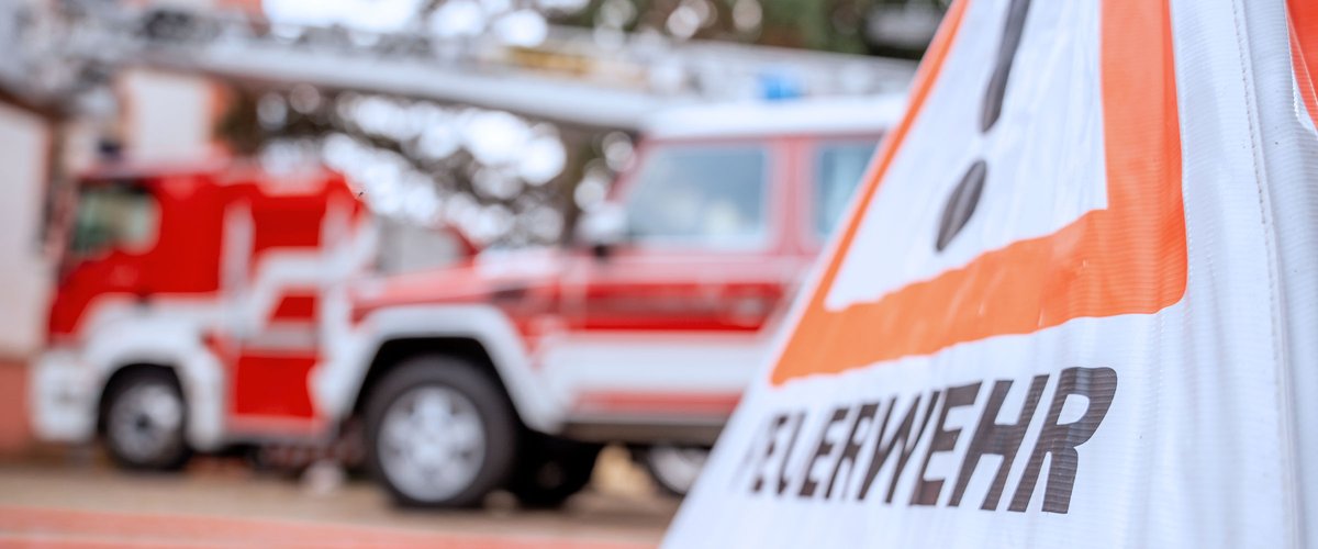 Feuerwehrfahrzeuge mit Warnschild im Vordergrund