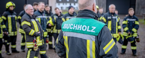 Feuerwehrmann in Uniform gibt Anweisungen an sein Team während einer Einsatzbesprechung.