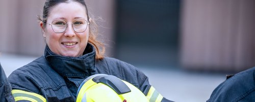 Feuerwehrfrau hält einen Helm in der Hand