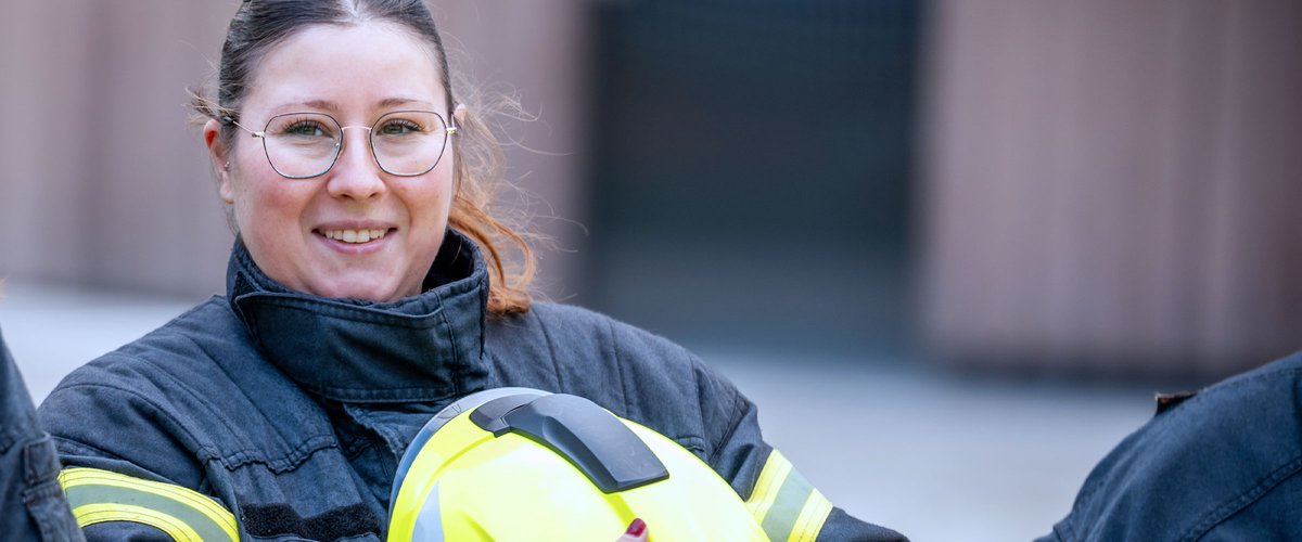 Feuerwehrfrau hält einen Helm in der Hand