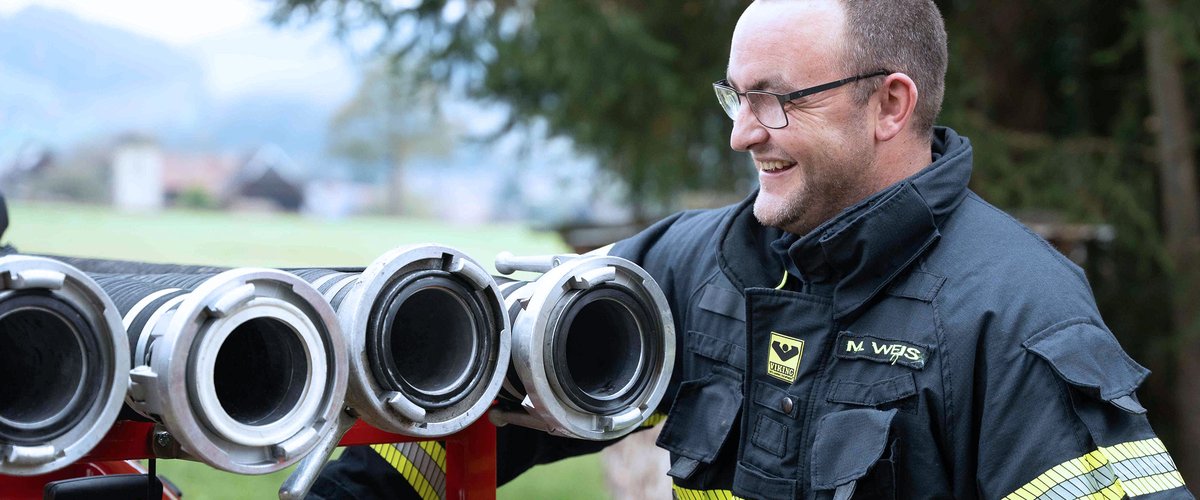 Feuerwehrmann bereitet sich auf den Einsatz vor, mit Saugschläuche im Vordergrund.